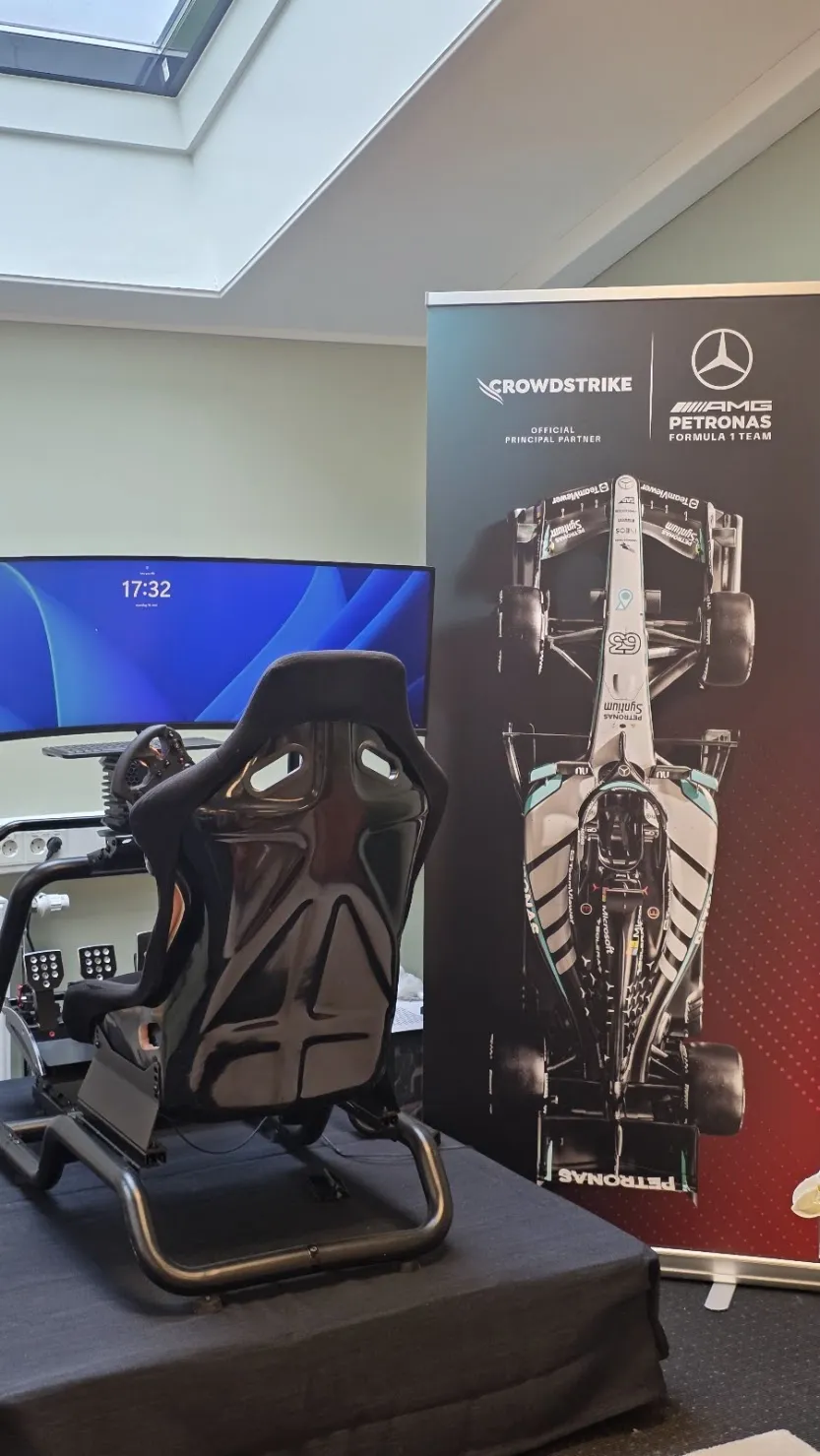 FMs racingsimulator-stol foran en CrowdStrike og Mercedes-AMG Petronas F1-rollup på kontoret